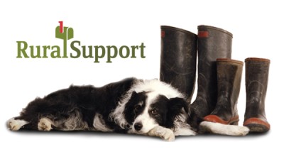 A farm dog sitting by two pairs of gumboots, with the Rural Support logo visible 